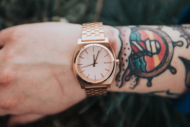 person wearing round gold analog watch