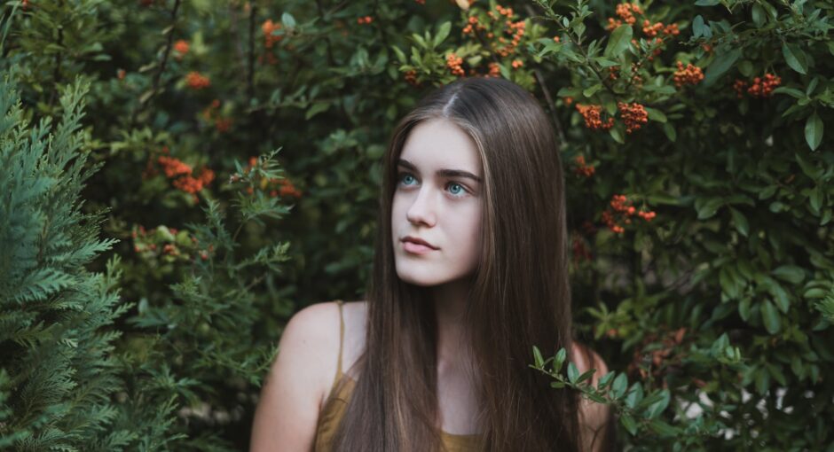 woman standing next to red flower