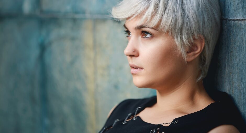 woman wearing black sleeveless top leaning on concrete wall